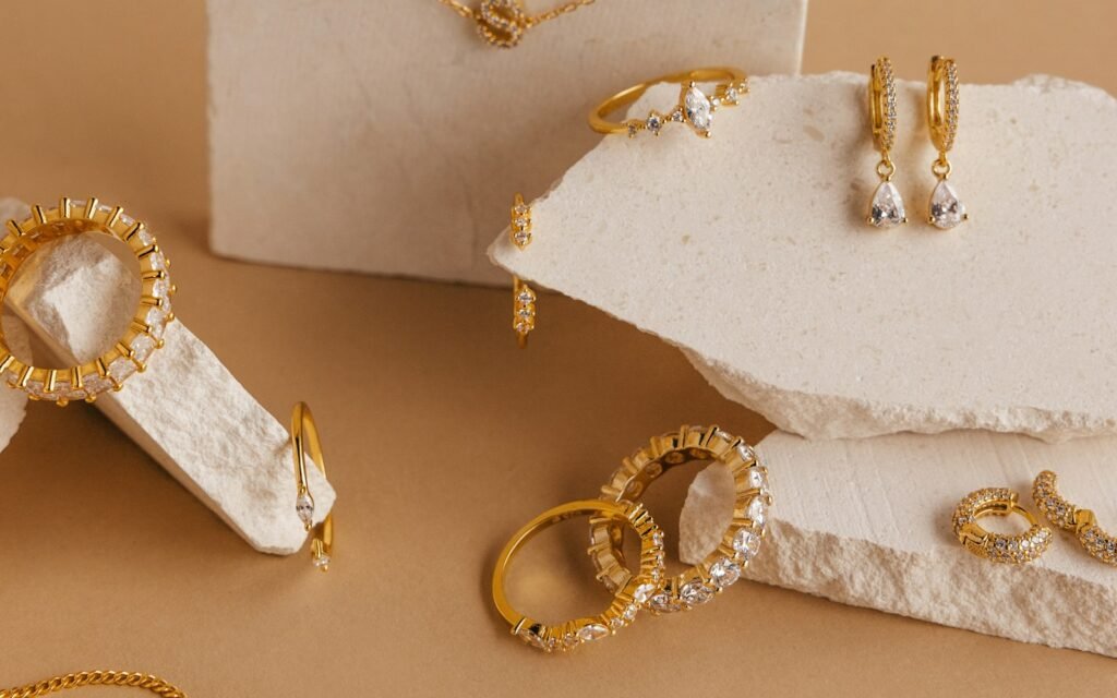 Gold necklaces, hoops and rings styled on beige stone