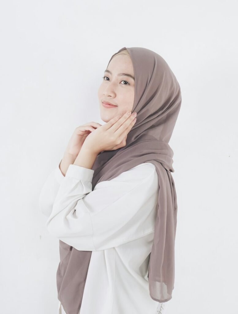 Woman in a taupe hijab and white shirt