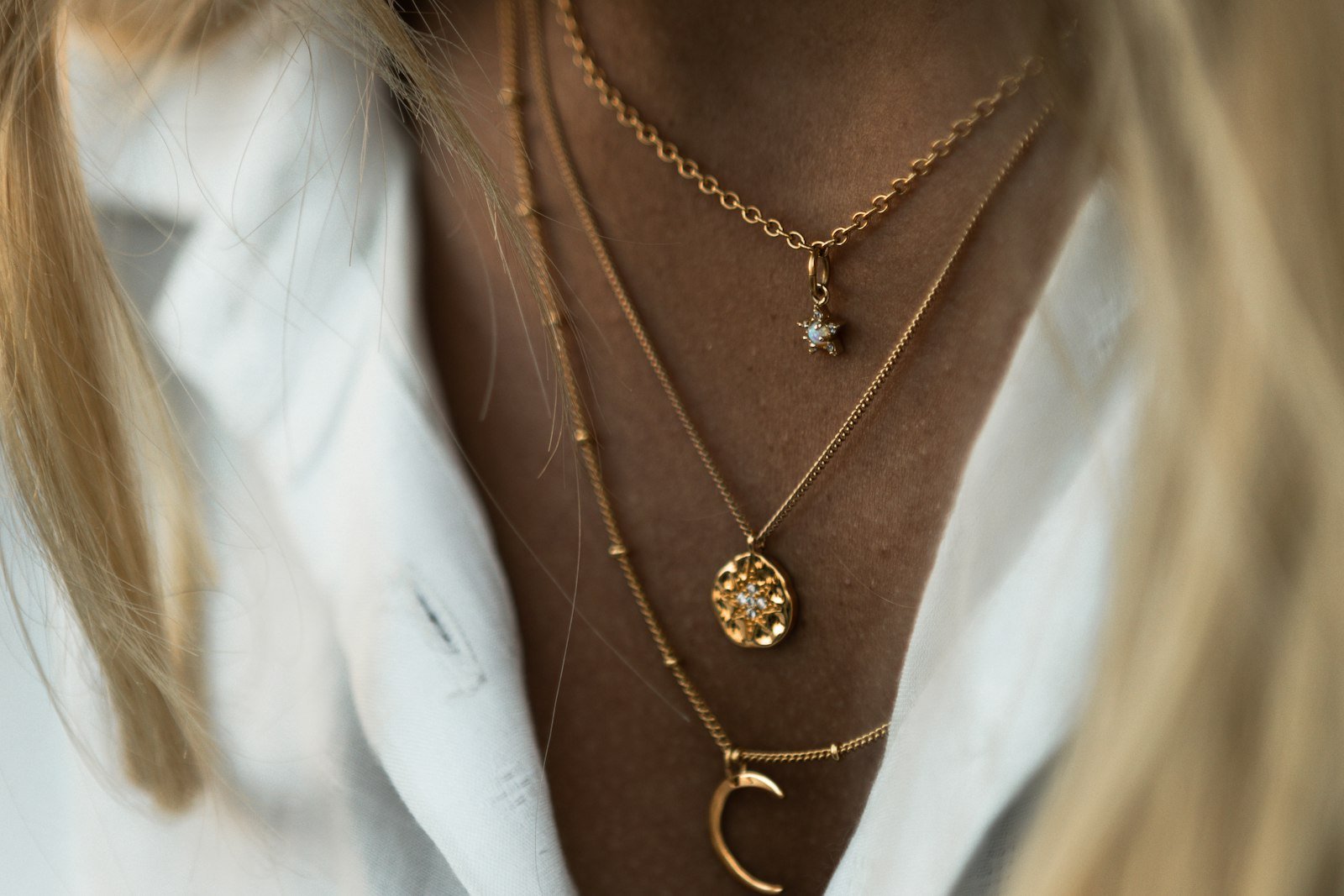 Layered gold necklaces worn with a white shirt