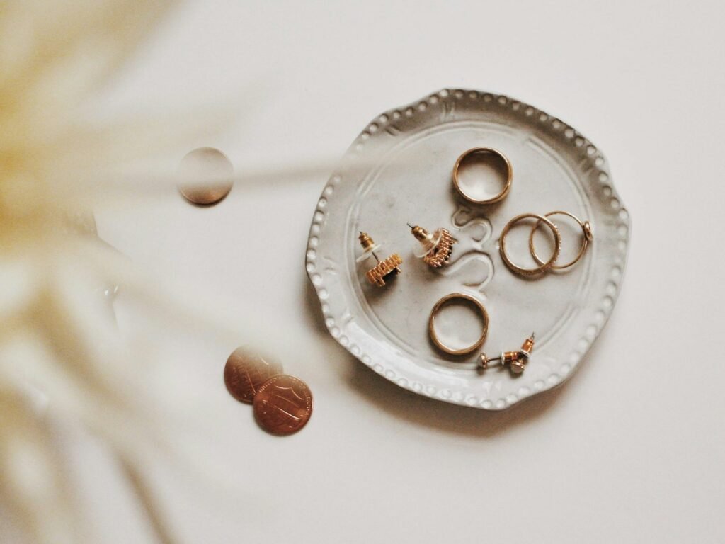 Gold rings and earrings resting on a ceramic dish