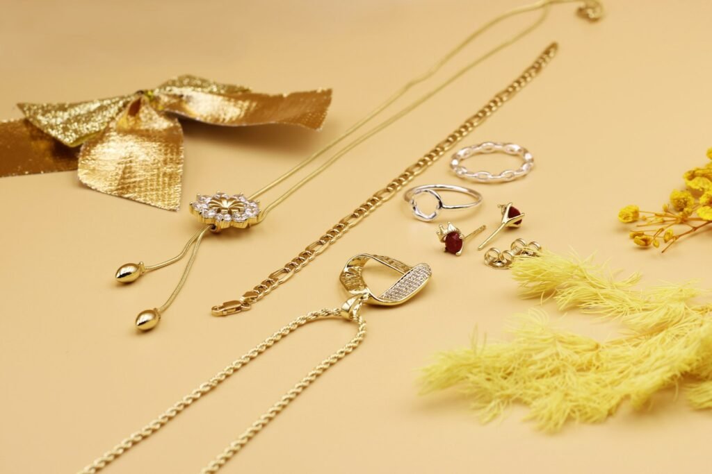 Gold necklaces and rings laid out on a warm beige surface