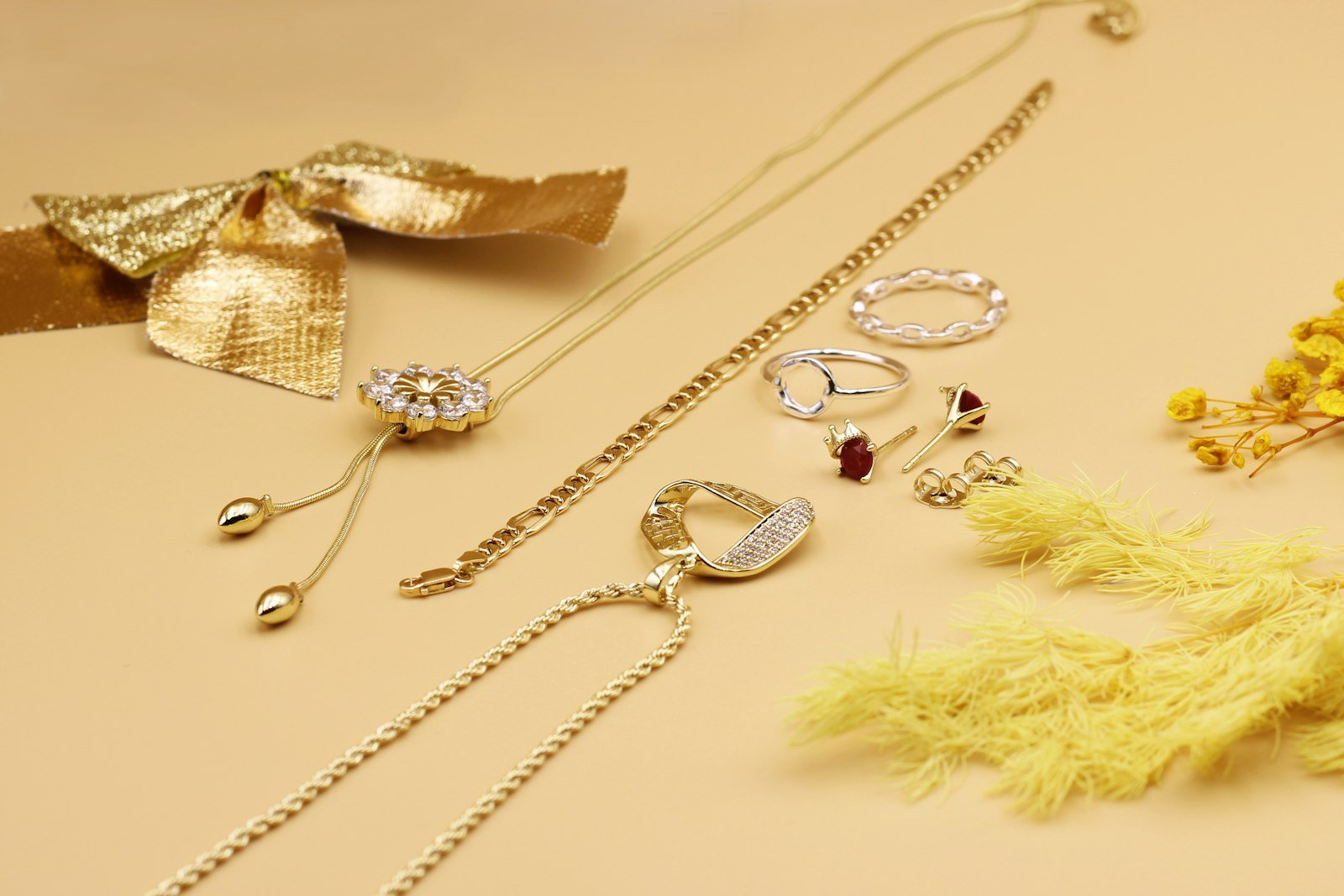 Gold necklaces and rings laid out on a warm beige surface