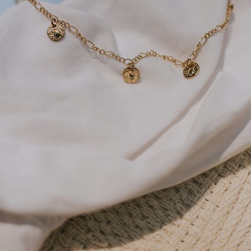 Gold initial charm necklaces on ivory fabric