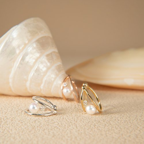 Pearl earrings next to a seashell